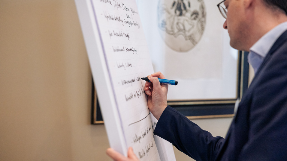 Sprecher notiert Inhalte an einem Flipchart während einer Session beim SZ-Versicherungstag 2026