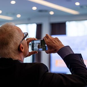 Mann fotografiert das Plenum während der E-world SZ-Führungstreffen Energie 2026